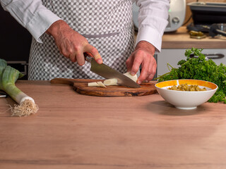 parsley root cut by the cook on a wooden board, vegetables healthy food, vegetarian cuisine, green parsley and leek, in front of the camera