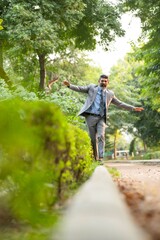 Fototapeta premium Indian businessman walking at park and giving happy expression