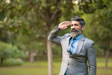 Indian man in suit and saluting at park
