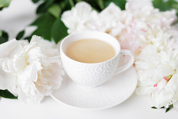 Morning romantic coffee cup, white peonies flowers on light background