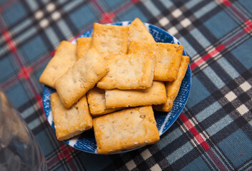 Plate of crispy rectangular salted crackers with sesame seeds on table. Traditional popular snack..