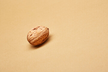 One alone unpeeled walnut isolated on the bright solid fond plain beige background