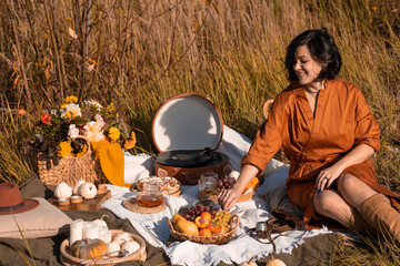 Fall picnic with pumpkin. Stylish woman enjoying autumn weather in the park. People, lifestyle, relaxation and vacations concept. Autumn harvest.