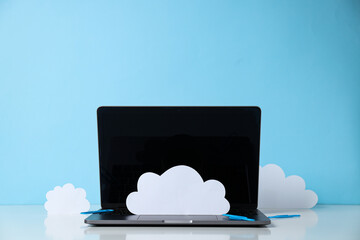 Laptop with paper clouds on a blue background