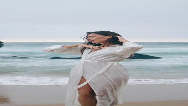 Tender woman dancing beach cloudy day. Girl moving seductively on shore vertical