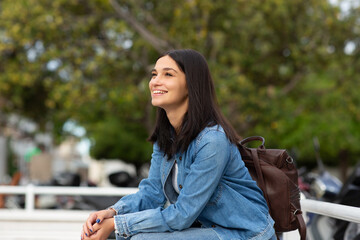 Side of smiling woman sitting outdoors