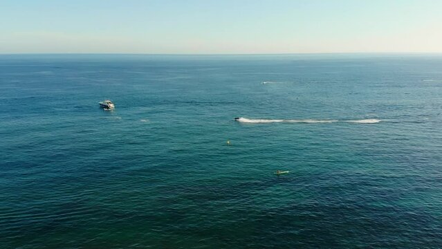 Drone shot of a jetski driving up to a boat.