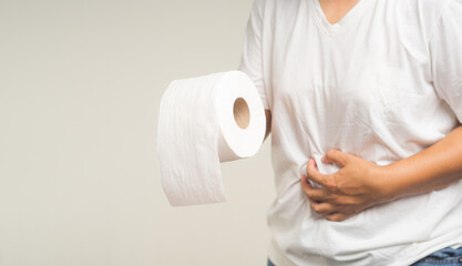 Hand holding a tissue and a painful stomachache while standing on a gray background.