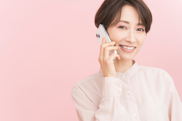 笑顔のミドル世代日本人女性/携帯電話で話している