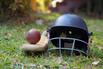 Cricket equipment is a cricket ball, cricket bat, cricket helmet on a grass background. Soft and...