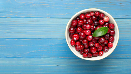 Cranberry with leaf in bowl on blue wooden background with copy space for your text. Top view