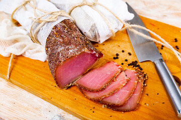 Smoked pork tenderloin sliced on wooden cutting board. Cured pork meat.