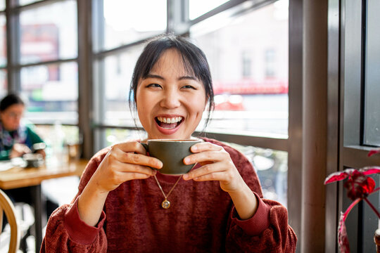 Asian small business owner working remotely on her laptop at a cafe
