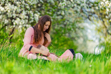 Naklejka na ściany i meble mother and daughter sit outdoors in a blooming garden
