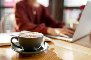 coffee on table of person working remotely on her laptop at a cafe
