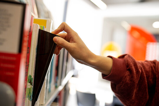 student at the library choosing a book from shelf