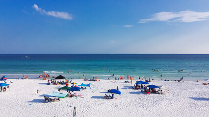 Fototapeta na wymiar Colorful beach umbrella and people swimming, laid-back relaxing on sugar-white sand beaches, crystal clear clean gorgeous shade of blue turquoise water Destin, South Walton, Florida, USA