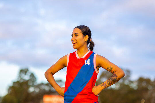 female football player in red and blue uniform standing with hands on hips