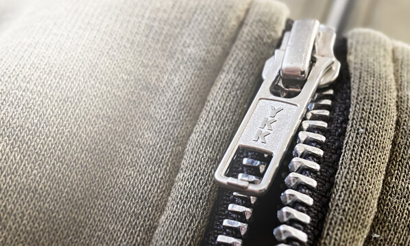 Close-up of YKK zipper on gray knit fabric with ribbed texture