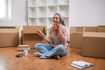 Modern ginger woman with braids talking on the phone while moving into her new apartment.