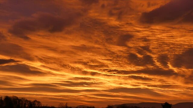Picturesque sky with moving clouds texture with illumination on by the rising sun over horizon with forest and Silesian Beskid mountains in Poland - time lapse.