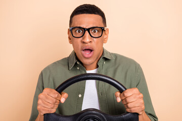 Photo of impressed shocked man wear khaki shirt spectacles rising vehicle isolated beige color background