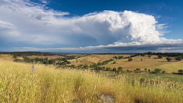 A dramatic storm cloud building over dry rural valley