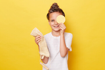 Smiling little girl with wet hair wearing casual white T-shirt standing isolated over yellow...