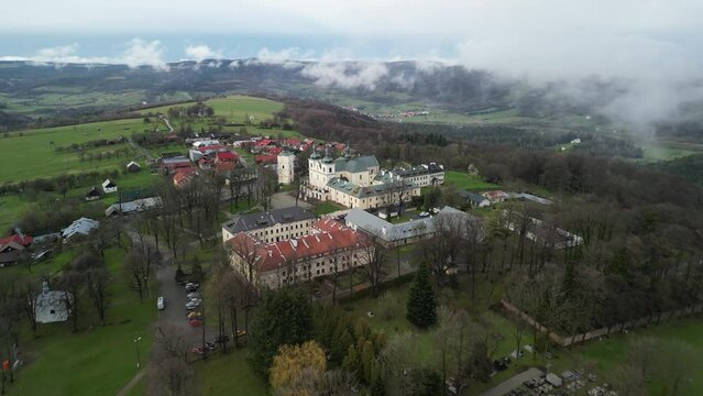 bird's-eye view of the sanctuary in Paclawska Calvary and the nearby historic wooden buildings of the village, with the Wiar river valley and the Przemyskie Foothills visible in the background 
