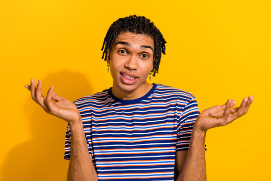 Portrait of clueless confused guilty man with piercing wear stylish t-shirt shrugging shoulders isolated on yellow color background