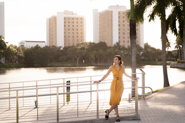 Young woman in yellow dress standing near water in city park