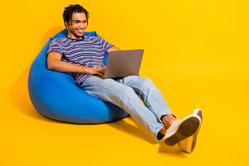 Full size photo of smart intelligent man wear stripped t-shirt sit on bean bag with laptop write...