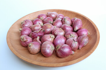 Red onion or shallots, on wooden plate, isolated on white background