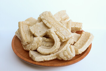 Kerupuk panjang, Indonesian snack or food condiment. Fried tapioca flour in long shape. On wooden plate, isolated on white background
