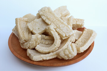 Kerupuk panjang, Indonesian snack or food condiment. Fried tapioca flour in long shape. On wooden plate, isolated on white background