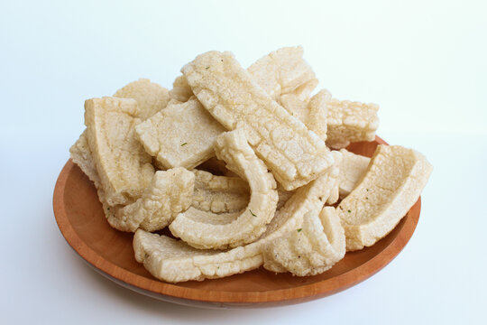 Kerupuk panjang, Indonesian snack or food condiment. Fried tapioca flour in long shape. On wooden plate, isolated on white background