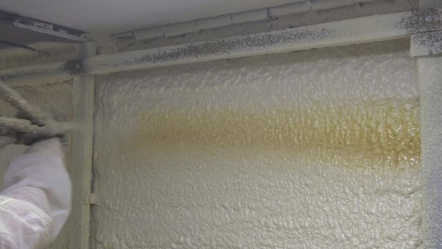 worker in a protective suit insulates the walls with polyurethane foam