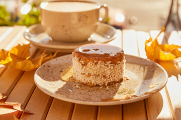 Fall healthy sweet carrot cake under agave syrup. No baking and no sugar dessert with cup of coffee under hard shadows