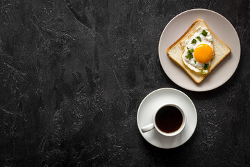 Obraz na płótnie Canvas Fried eggs on toast bread and cup of black coffee, top view