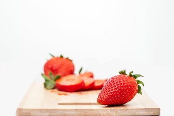 Fresh red strawberries and a knife on a wooden cutting board.