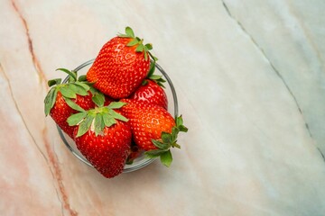 Bowl containing fresh strawberries on a wooden kitchen countertop.