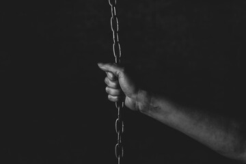 Hand of a person chained on black background, feeling a lack of freedom, prison