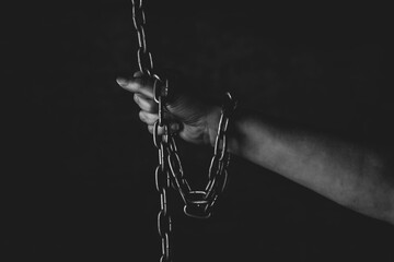 Hand of a person chained on black background, feeling a lack of freedom, prison