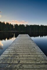 Idyllic scene of a wooden dock extending out onto a serene lake at sunset