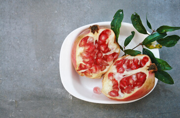 Fresh ​​pomegranate fruit half cut in white bowl showing beautiful juicy red seeds