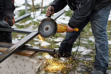Close up of man grinding metal with circular grinder disc and electric sparks. Worker cutting metal with angle grinder for welding. Workers making fence with shielded metal arc welding