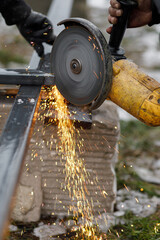 Close up of man grinding metal with circular grinder disc and electric sparks. Worker cutting metal...
