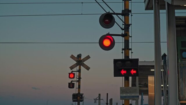 A flashing red railroad crossing warning light in the autumn countryside