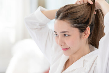 Beautiful Asian young woman tie the hair back before shower or apply cream or lotion on face. Beauty female grab her hairs after wake up with happiness and positive emotional. Self care concept - Powered by Adobe