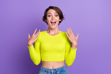 Obraz na płótnie Canvas Photo of impressed nice cheerful person raise arms open mouth cant believe wear lime cropped top isolated on violet color background